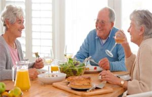 Две женщины и мужчина кушают за столом картинка